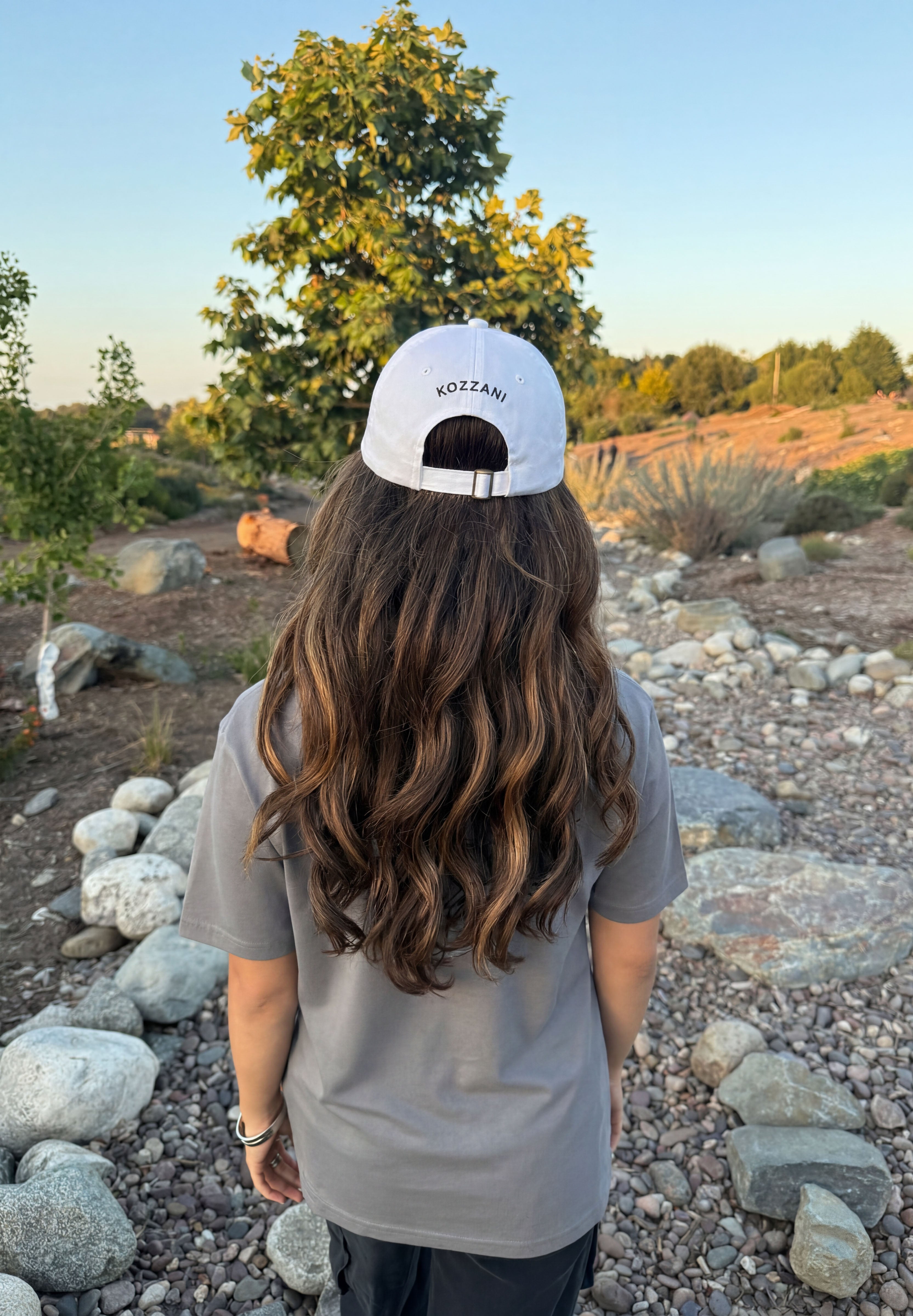 White baseball cap worn back with small logo on the crown